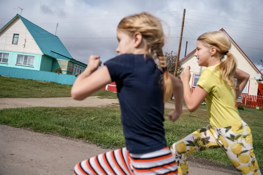 Даша и&nbsp;Полина Фельхле бегут по&nbsp;селу Корнилово в&nbsp;150&nbsp;км от&nbsp;Новосибирска. Их&nbsp;папа Юрий работал слесарем, потом перешел в&nbsp;местный сельский свинокомплекс, который в&nbsp;2022 году закрыли из-за долгов. Чтобы содержать семью, Юрий берется за&nbsp;любую подработку. Его семье помог центр поддержки семей и&nbsp;детей «Вместе». Фото: Дмитрий Яцюк.