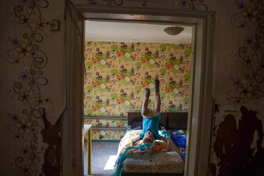 Артём Чукавин кувыркается на&nbsp;своей кровати, село Мочище, Новосибирская область. У&nbsp;него есть пять братьев и&nbsp;сестёр. Центр поддержки семей и&nbsp;детей «Вместе» закупил для Чукавиных дрова и&nbsp;уголь на&nbsp;зиму, чтобы дети не&nbsp;оказались в&nbsp;приюте. Фото: Дмитрий Яцюк.